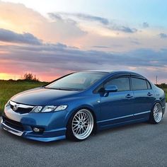 a blue car is parked on the side of the road in front of an orange sunset