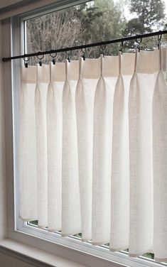 a window with white curtains hanging from it's side