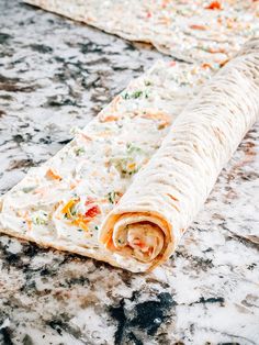 a rolled up burrito sitting on top of a marble counter covered in confetti