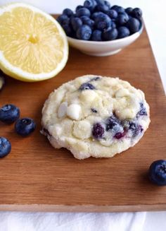 a cookie with blueberries and lemons on a cutting board next to some fruit