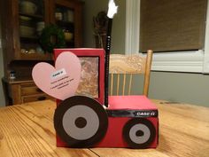 a wooden table topped with a red truck and heart shaped card box sitting on top of it