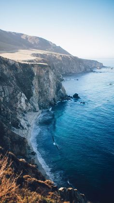 an ocean view from the top of a hill with cliffs in the foreground and blue water below