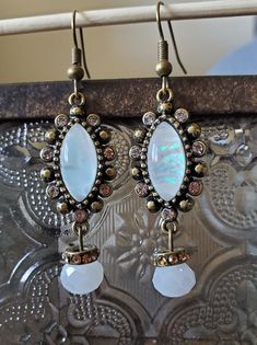 These 1920's inspired earrings are made of brass hooks, base, and spacers. The spacers have small yellow rhinestones. The main focal piece has faux shell centers with rhinestones along the edge. Vintage Crystal Drop Earrings With Ear Wire, Vintage Jeweled Dangle Crystal Earrings, 1920s Jewellery, 1920s Jewelry, Brass Hooks, Costume Earrings, Brass Hook, 1920s Fashion, Jewelry Inspo