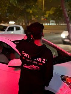 a person standing next to a pink car