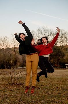 two people jumping in the air with their hands up