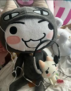 a cat stuffed animal with headphones attached to it's ears, sitting on a bed