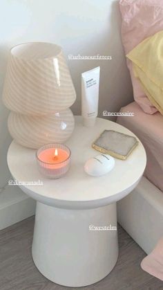 a small table with a candle and some items on it next to a bed in a room