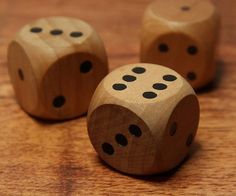 three wooden dices sitting on top of a wooden table with holes in the middle