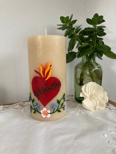 a candle that is sitting on a table next to a vase with flowers in it