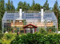 a house with a glass roof surrounded by greenery and trees in the foreground