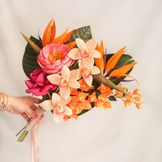 a bouquet of flowers is being held by a woman's hand on a white background