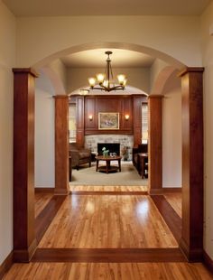 an empty living room with wood flooring and chandelier