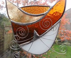 a stained glass sun catcher hanging on a window sill in front of a tree