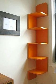 an orange shelf in the corner of a room next to a window with a framed picture on it