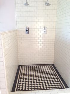 a black and white checkered floor in a shower stall with two faucets