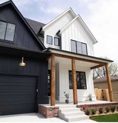 a black and white house with two garages on the front, and an attached porch