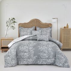 a bed with grey and white comforters in a room