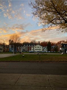 the sun is setting over some houses and trees in this suburban area with no cars or people