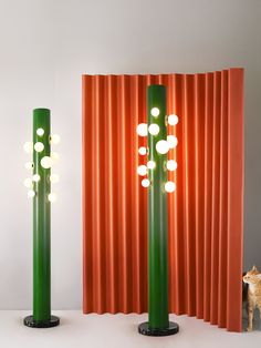 two tall green and orange lamps sitting next to each other on top of a table