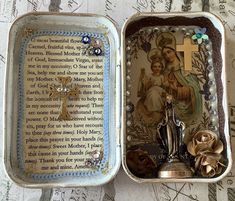 an open tin box with a cross and rosary in it on top of a table