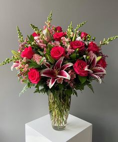 a vase filled with red roses and pink lilies