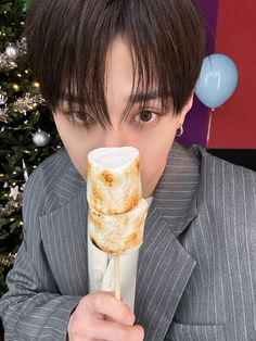 a man in a suit is holding up a large piece of food to his face