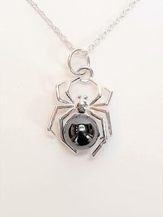 A sterling silver spider pendant with shiny Haematite stone. Comes with its own sterling silver chain.A 6mm ball of natural Haematite stone sits in the centre of a sterling silver spider, ideal for Halloween wear or as a gift for a spider lover. Complete with dainty sterling silver chain.With a shorter chain, this spider necklace hangs roughly on the upper chest area when worn.Total length of spider necklace (from clasp to bottom of pendant): Approximately 22cm / 8.6"Pendant length: Approximatel Diy Spider Necklace, Silver Hematite Necklace Gift, Spider Choker Necklace, Spider Inspired Jewellery, Spider Jewelry Vintage, Silver Spider Necklace, Spider Pendant, Spider Necklace, Gothic Jewellery