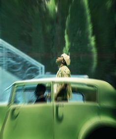 a man standing in front of a green car