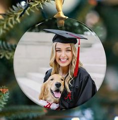 a woman wearing a graduation cap and gown holding a golden retriever dog in front of a christmas tree