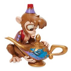 a monkey figurine sitting on top of a teapot with a cup in it