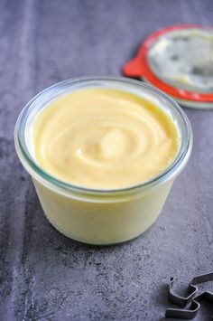 a small glass bowl filled with yogurt sitting on top of a table next to a pair of scissors