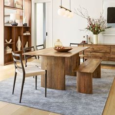 a dining room table with two benches in front of it and a television on the wall