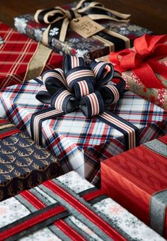 many wrapped presents are stacked on top of each other with ribbons and bows around them