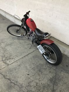 a red motorcycle parked next to a white wall