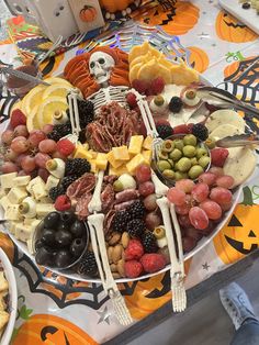 a platter filled with fruit, cheese and skeleton figurines on top of a table