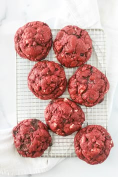 red velvet cookies on a cooling rack with white napkins next to them and one cookie in the middle