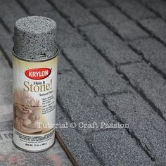 a can of krylon hair stone sitting on the ground next to a brick wall