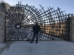 a man standing in front of a large metal gate