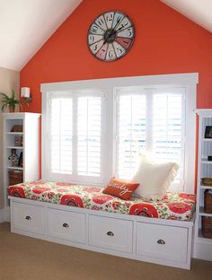 a window seat with pillows and a clock on the wall