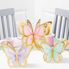 two paper butterflies sitting on top of a table next to plates and cups with napkins