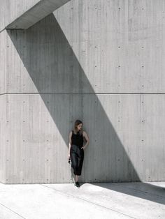 a woman standing in front of a concrete wall