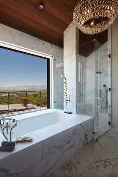 a bathroom with a large tub next to a window and a chandelier hanging from the ceiling