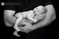 a black and white photo of a man holding a newborn baby in his arms,