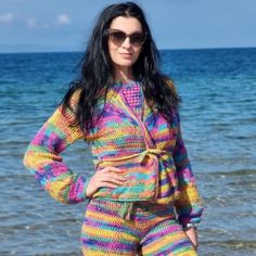 a woman is standing on the beach with her hands on her hips