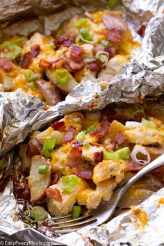 a close up of food on foil with a fork and spoon in the foreground