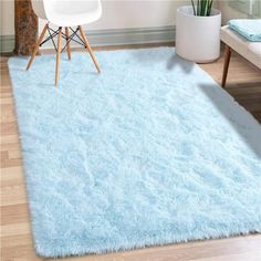 a blue shaggy rug in the corner of a room with a white chair and table