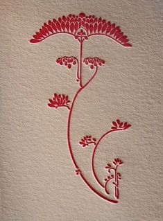 an intricately designed card with red flowers on the front and bottom, in white paper