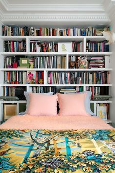 an image of a bed with bookshelves in the background and pink pillows on it