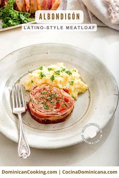 a white plate topped with meat and mashed potatoes next to a knife and fork