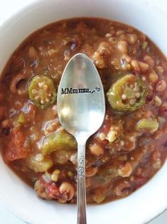 a white bowl filled with beans and veggies next to a spoon that says mmm